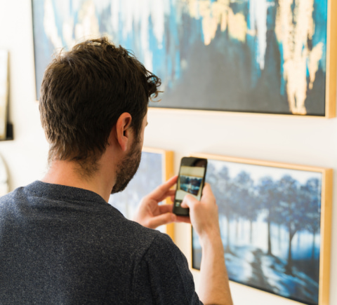 Young person taking a photograph of a painting with his phone